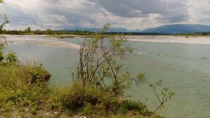 Un fiume con un argine erboso e montagne sullo sfondo.