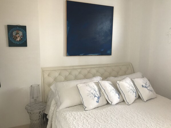 A bedroom with a bed, a nightstand, a lamp, and two wall decorations.
