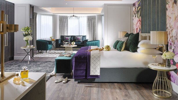 Et moderne hotelværelse med en stor seng, en sofa, et rundt sofabord og et lille sengebord.