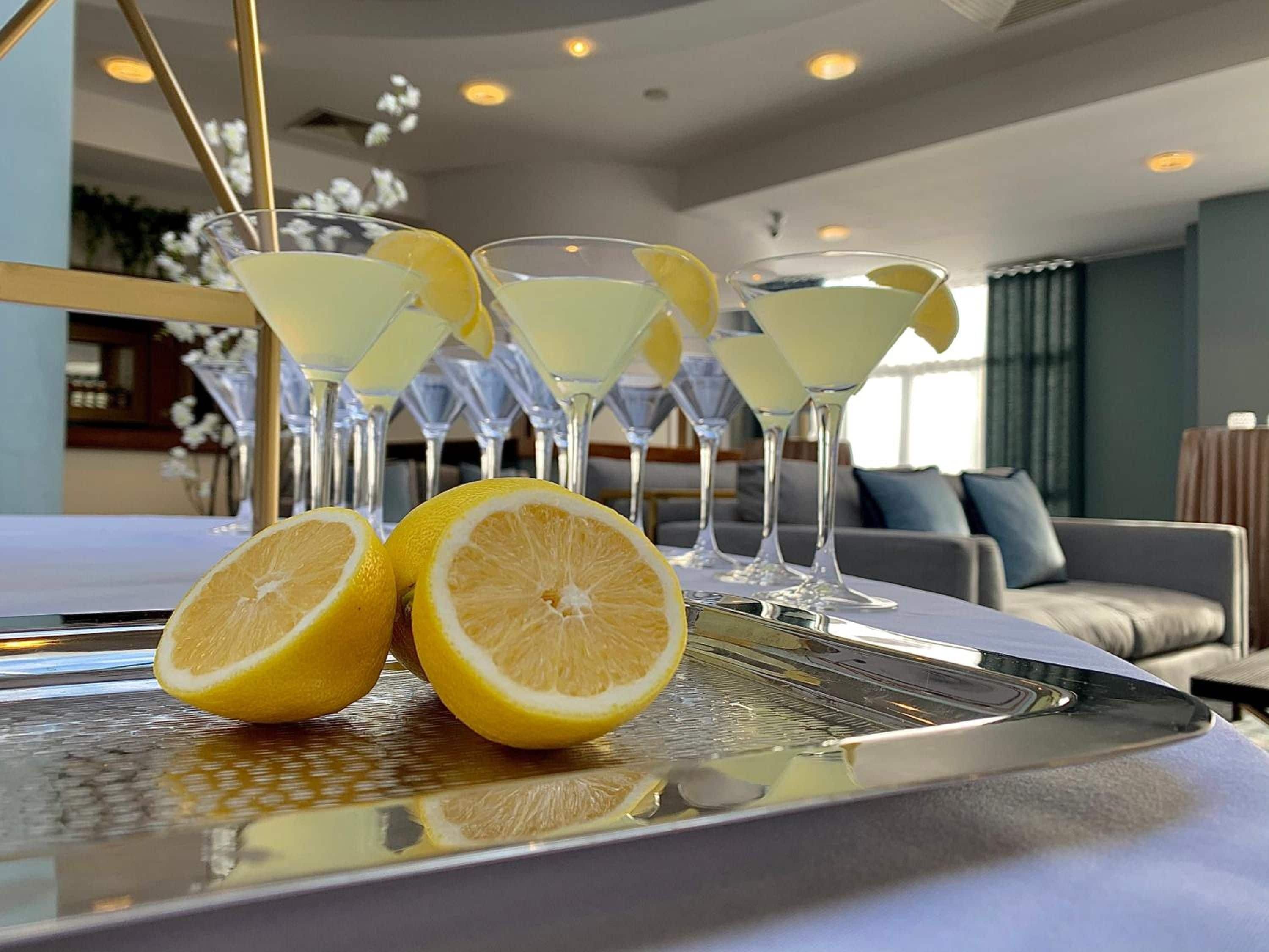 Una zona de bar con una bandeja de copas de martini y rodajas de limón.