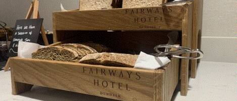 Un expositor de madera con el texto 'FAIRWAYS HOTEL' y 'DUNDIE', que contiene varios tipos de pan.