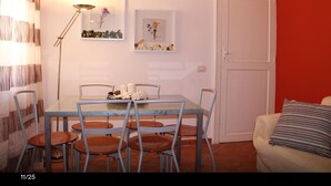 Uma área de refeições com mesa, cadeiras, uma luminária e obras de arte nas paredes.