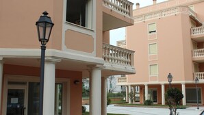 A multi-story building with balconies, a covered entrance, and a well-maintained lawn. - Geranei Appartamento Bilocale a 50 metri dal mare (TAGGIA)