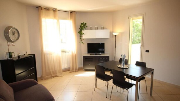 A compact living space with a dining area, a sofa, a TV, and a small kitchen. - Geranei Appartamento Bilocale a 50 metri dal mare (TAGGIA)