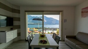 Un espace repas comprenant une table, des chaises et offrant une vue sur les montagnes et un lac.
