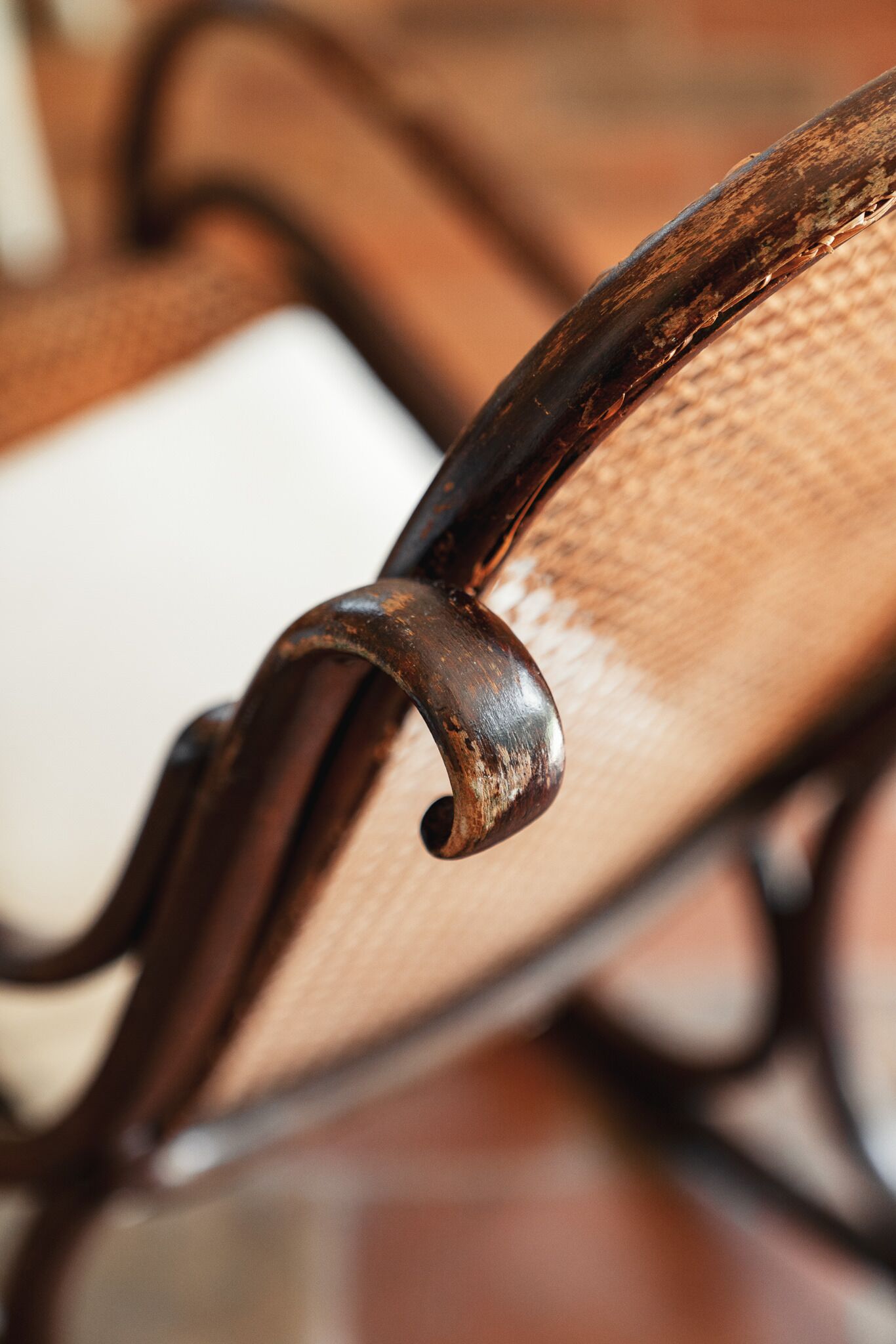 A close-up of a chair's metal armrest with a textured fabric seat.