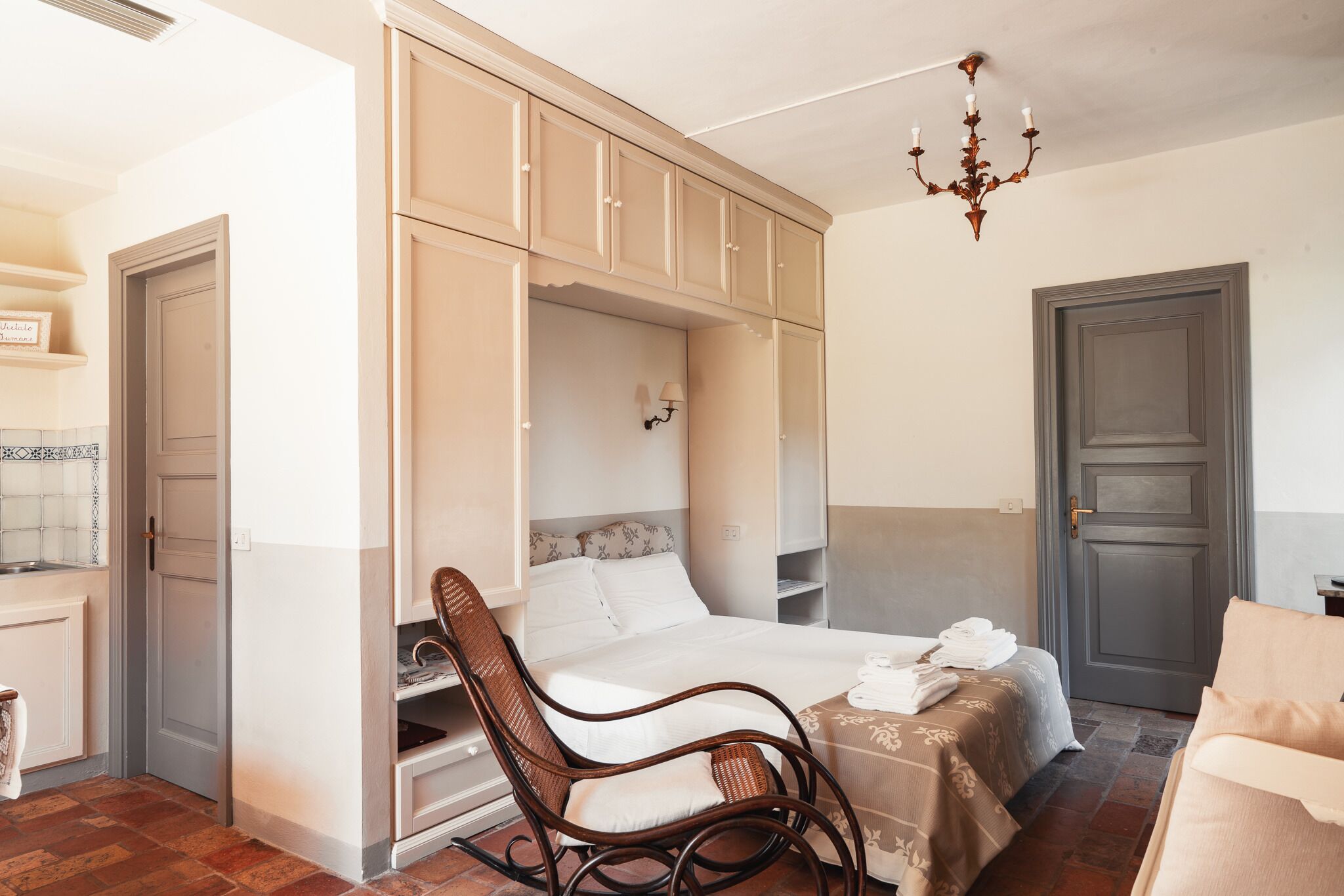 Ein Schlafzimmer mit Bett, Stuhl, Kleiderschrank und einer Deckenleuchte.