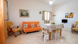 A living room with a sofa, a dining table, and a TV.