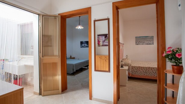 A spacious room with a large window, a wooden door, and a bed with a floral bedspread.