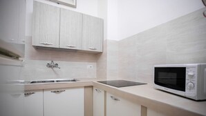 A small kitchen with white cabinets, a sink, and a microwave.
