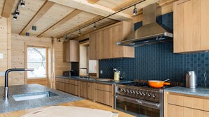 Eine moderne Küche mit Holzausstattung, einem Edelstahlherd und einer schwarzen Küchenrückwand.