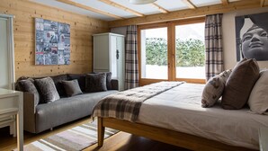 Ein Schlafzimmer mit einem Bett, einer Couch, einem Kleiderschrank und einem Fenster mit Vorhängen.