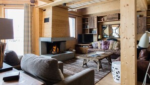 Ein gemütliches Blockhaus-Interieur mit Kamin, Holzmöbeln und einer Bücherwand.
