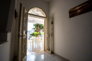 A hallway with a decorative door leading to an outdoor area with a table and chairs. - Holiday house with garden, Torre Lapillo (TL65) (Torre Lapillo)