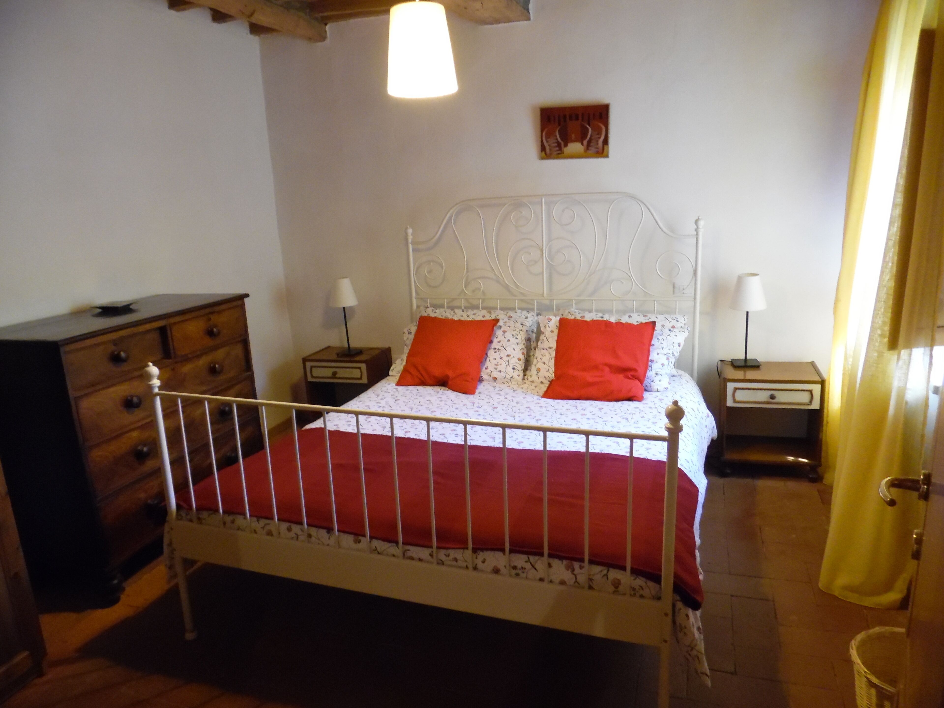 A bedroom with a bed, two nightstands, a dresser, and a wall-mounted picture.