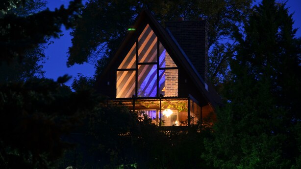 A modern house with a triangular roof, large windows, and a visible interior light. - ONE OF A KIND vacation rental with a view (Madison)