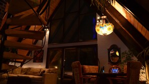 A cozy room with a high ceiling, wooden beams, a dining table with chairs, a sofa, and a hanging light fixture. - ONE OF A KIND vacation rental with a view (Madison)