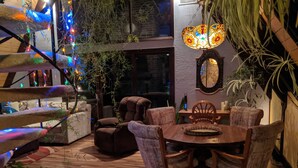 A cozy dining area with a wooden table and chairs, surrounded by plants and a staircase with colorful lights. - ONE OF A KIND vacation rental with a view (Madison)