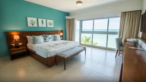 A hotel room with a large bed, a desk, and a view of the ocean.