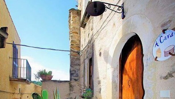 A narrow alleyway with a stone wall, a wooden door, and a sign that reads "Cava". - Characteristic house in the historic centre of Belmonte Calabro, Nature and Culture (Belmonte Calabro)