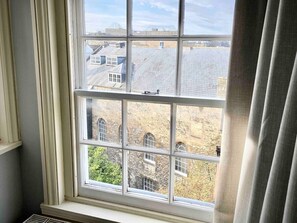 A window with multiple panes, offering a view of buildings and greenery outside. - Central Bath - Gorgeous Loft Apartment (TLA) (Bath)