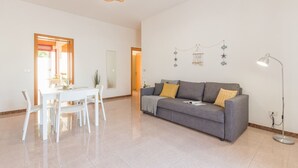 Ein großzügiger Wohnbereich mit grauem Sofa, weißem Esstisch und Stühlen.