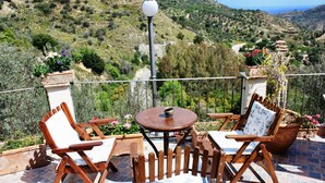 A terrace with wooden chairs and a table, overlooking a mountainous landscape with a clear sky. - Apartment in a studio villa called Salina 3 beds (REITANO)