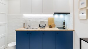 A compact kitchen with a sink, a wooden countertop, and blue cabinets. - Acropolis Heart 2BD Apartment in Plaka (Athens)