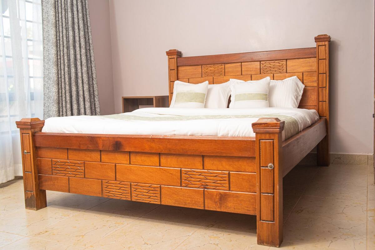 A wooden bed with a headboard, white bedding, and a nightstand.