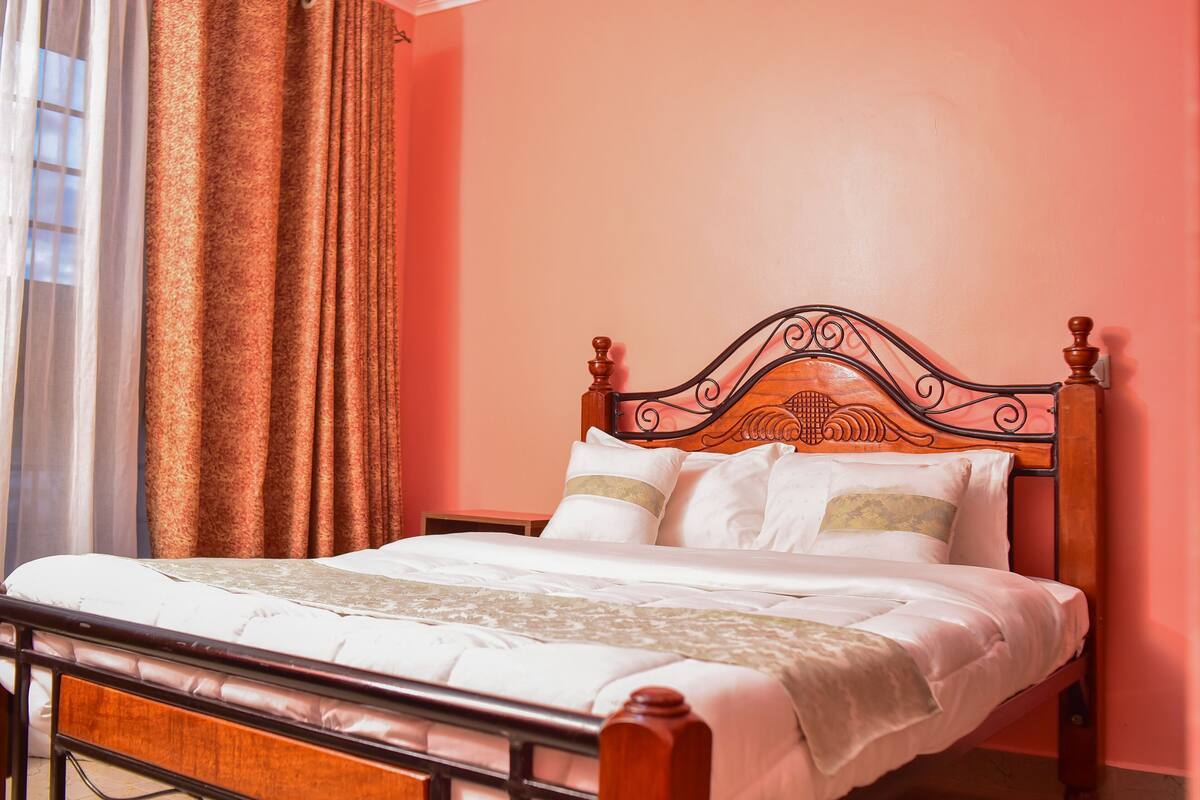 A neatly made bed with a wooden headboard, white bedding, and a patterned throw.