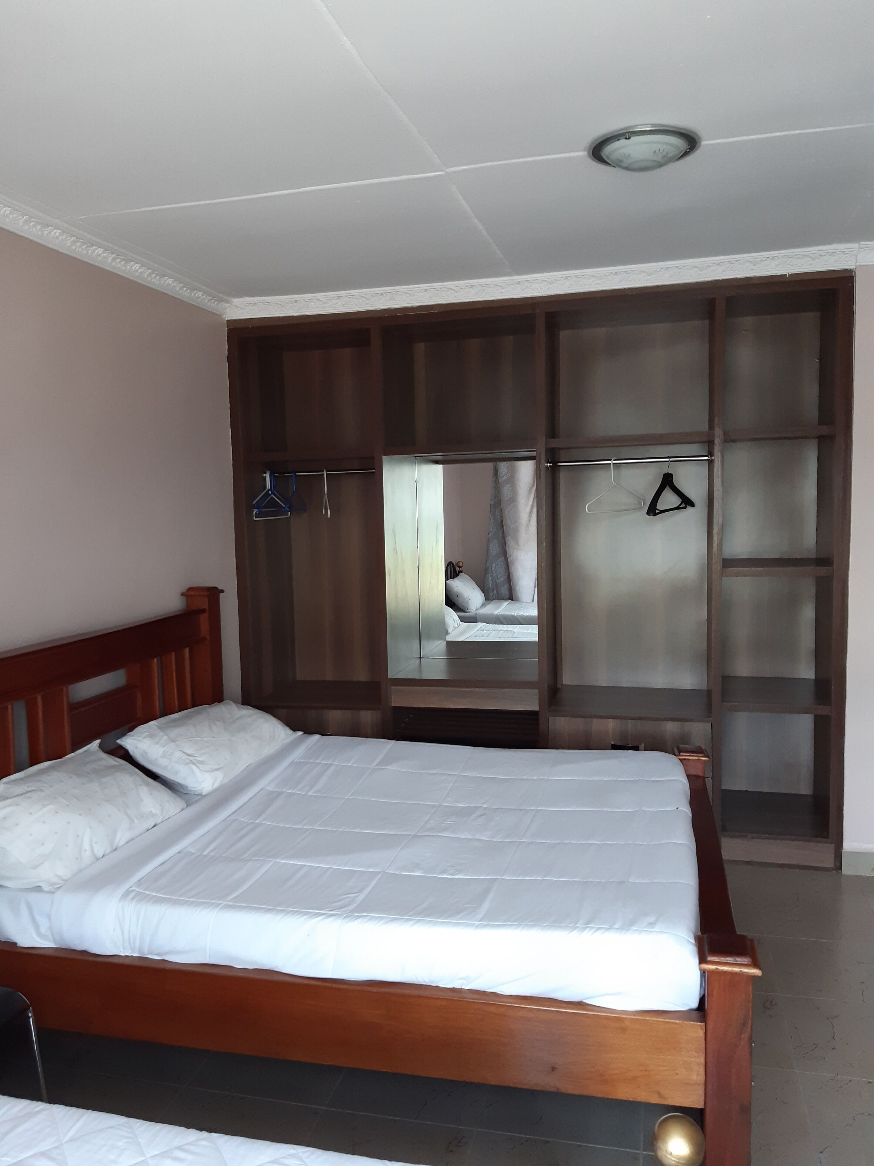 A bedroom with a wooden bed, a wardrobe with a mirror, and a hanging clothes rack.