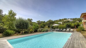 Ein rechteckiger Pool mit klarem, blauem Wasser, umgeben von einer Holzterrasse.