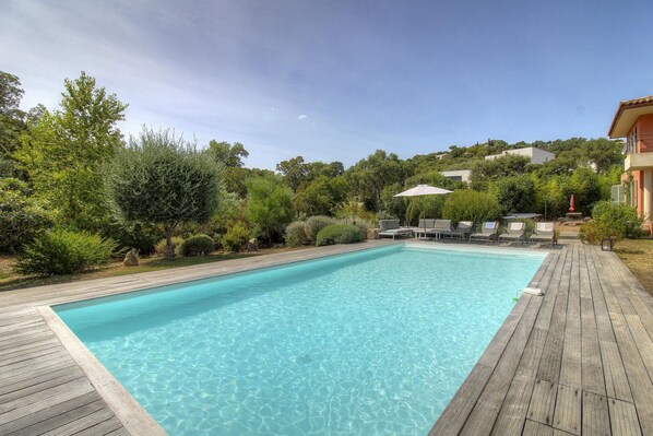 A rectangular swimming pool with clear blue water, surrounded by a wooden deck.