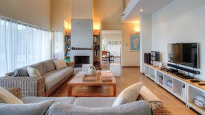 Ein geräumiges Wohnzimmer mit Kamin, einer Couch, einem Couchtisch und einem Fernseher.