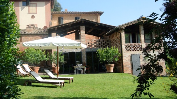 Une cour avec une piscine, des chaises longues et une table placée sous une pergola.