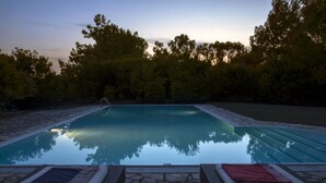 Una piscina con borde de piedra y sillas de descanso con toallas.