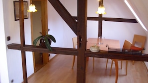 A dining area with a wooden table, chairs, and a vase of flowers. - Messewohnung Gräfrath (Solingen)