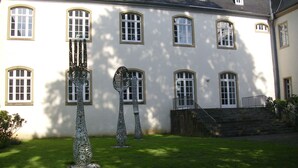 A building with multiple windows and a staircase leading to a balcony. - Messewohnung Gräfrath (Solingen)