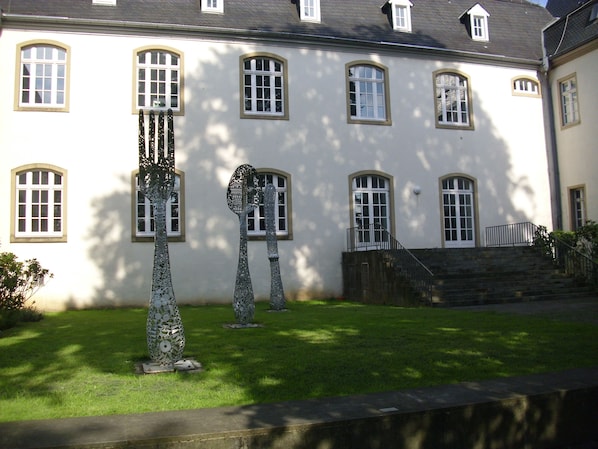 A building with multiple windows and a staircase leading to a balcony. - Messewohnung Gräfrath (Solingen)