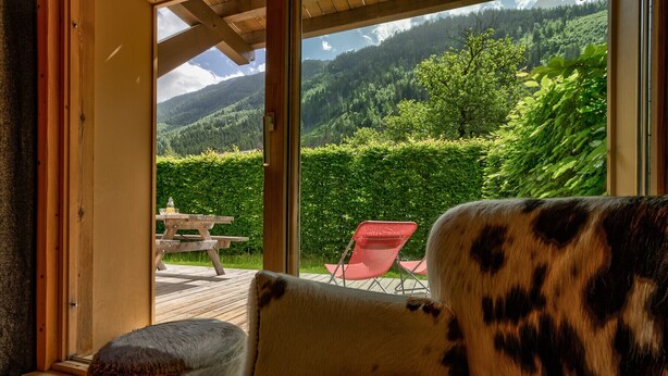 Una habitación con vistas a una cadena montañosa boscosa a través de amplios ventanales.