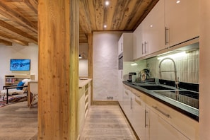 A modern kitchen with wooden beams, a large island, and a view of the mountains.