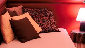Ein Bett mit mehreren Kissen und einem Nachttisch mit Lampe.