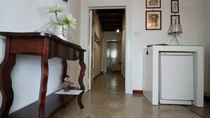 Ein Flur mit einer Holzbank, einem weißen Kühlschrank und einer Blumenvase.