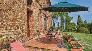 Ein Steingebäude mit Terrasse, Sitzgelegenheiten im Freien und Kübelpflanzen.