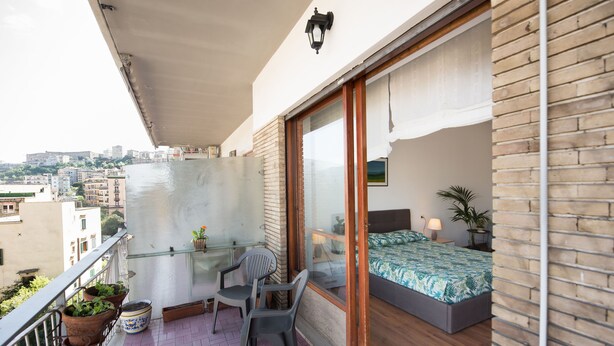 A balcony with a bed, a chair, and potted plants. - Panorama Vesuvius 3 (Central) private room in apartment (Napoli)