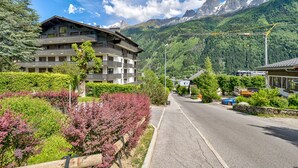 Un hotel de varios pisos con balcones, rodeado de vegetación exuberante y un telón de fondo montañoso.