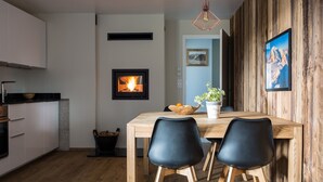 Una cocina moderna con chimenea empotrada, mesa de comedor de madera y sillas negras.