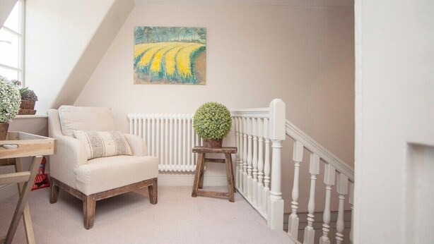 Een knus vertrek met een witte radiator, een houten stoel, een klein tafeltje en een potplant.