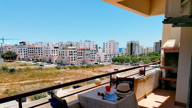 Un balcon avec une table, une chaise et une vue sur le paysage urbain.