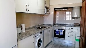 Une cuisine compacte équipée d’un lave-linge, d’un four à micro-ondes et d’un évier.